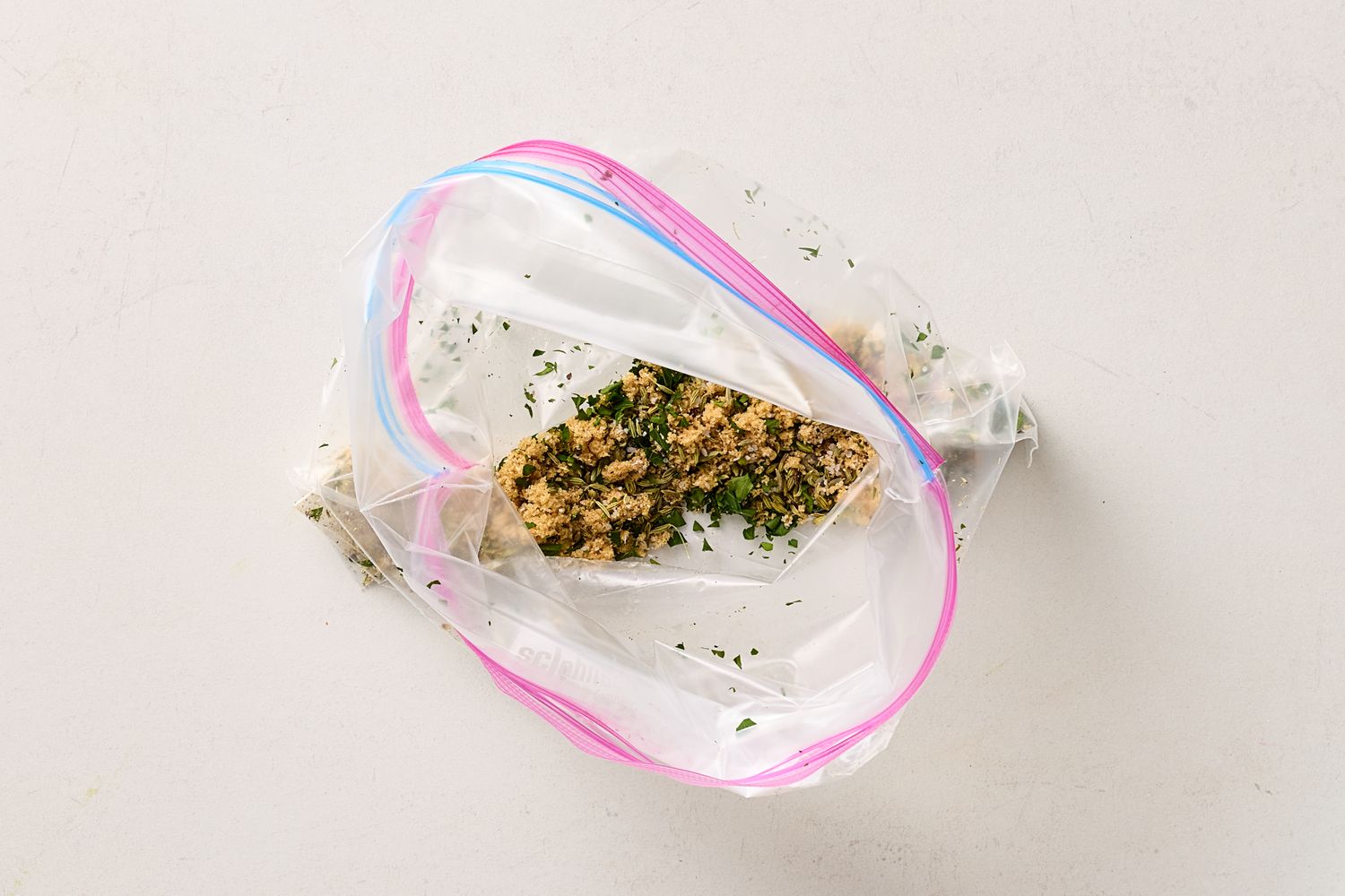 Plastic bag containing a mixture of chopped herbs and what appears to be ground food or salmon prepared for a recipe