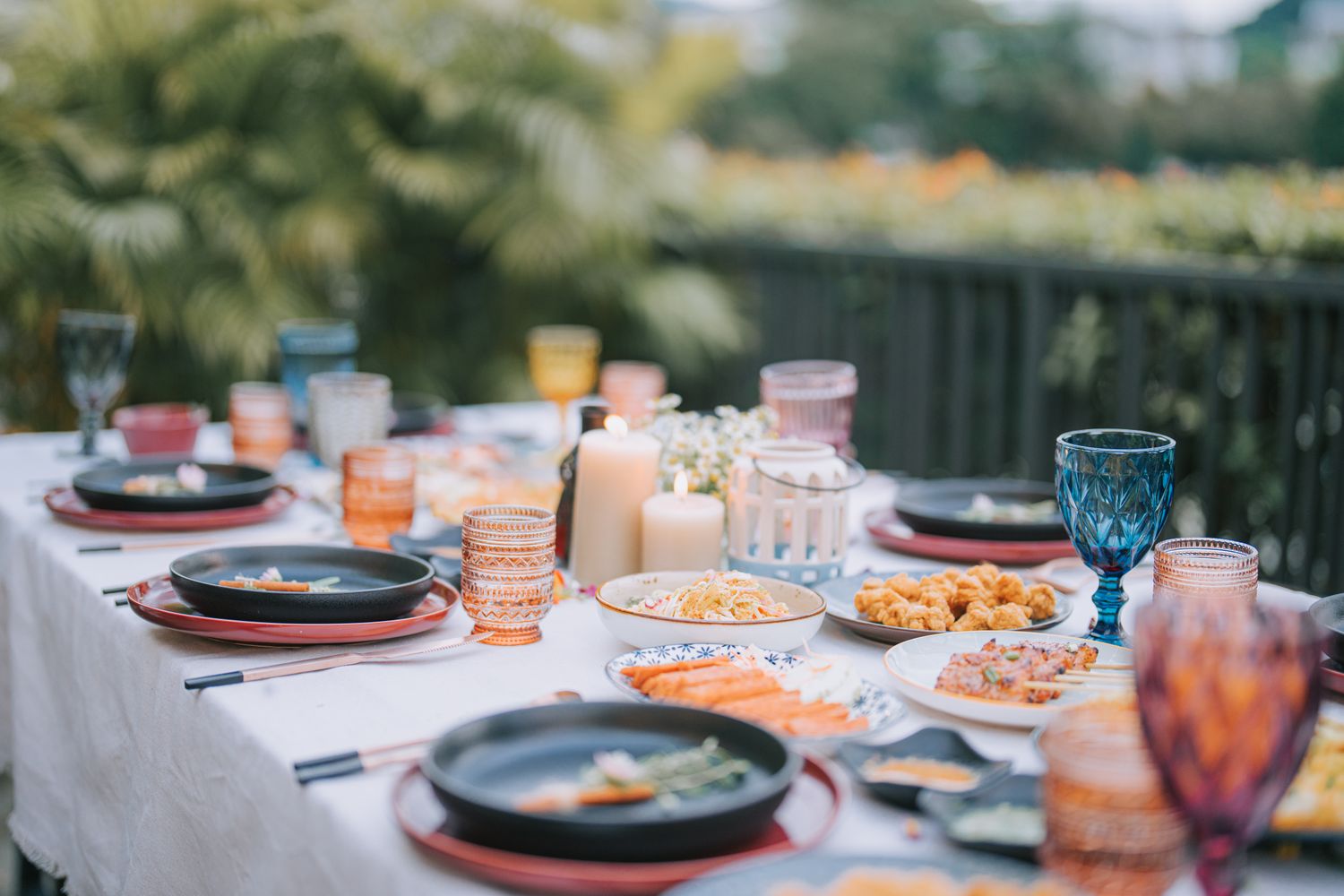 Table set for an outdoor dinner with plates glasses and assorted dishes