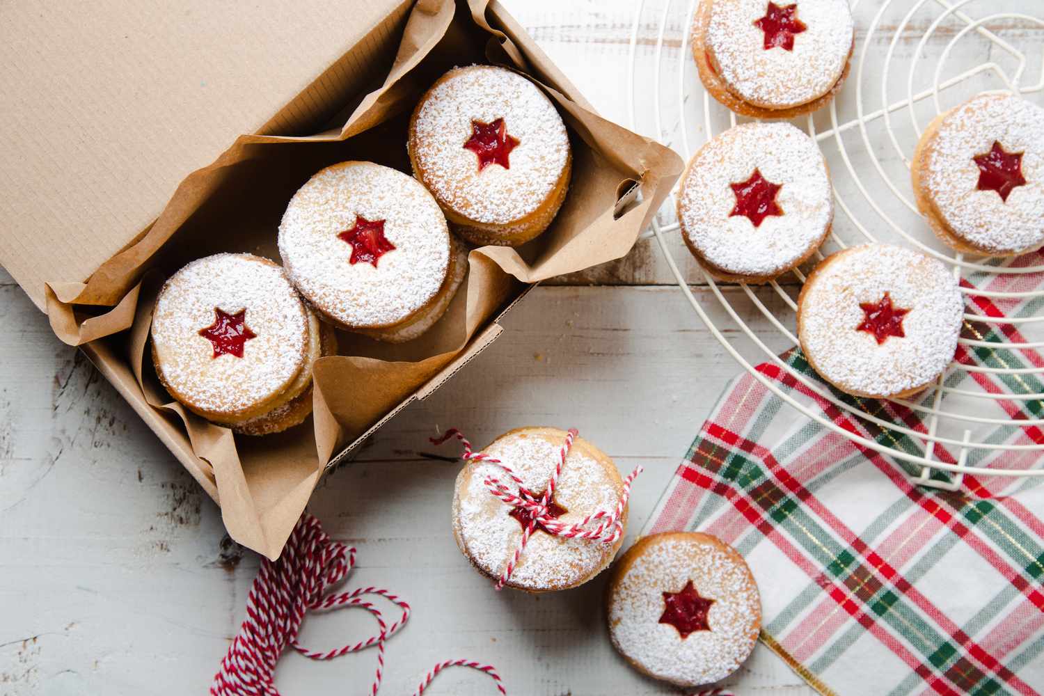 A box of startopped pastries with red filling a tray and tablecloth nearby