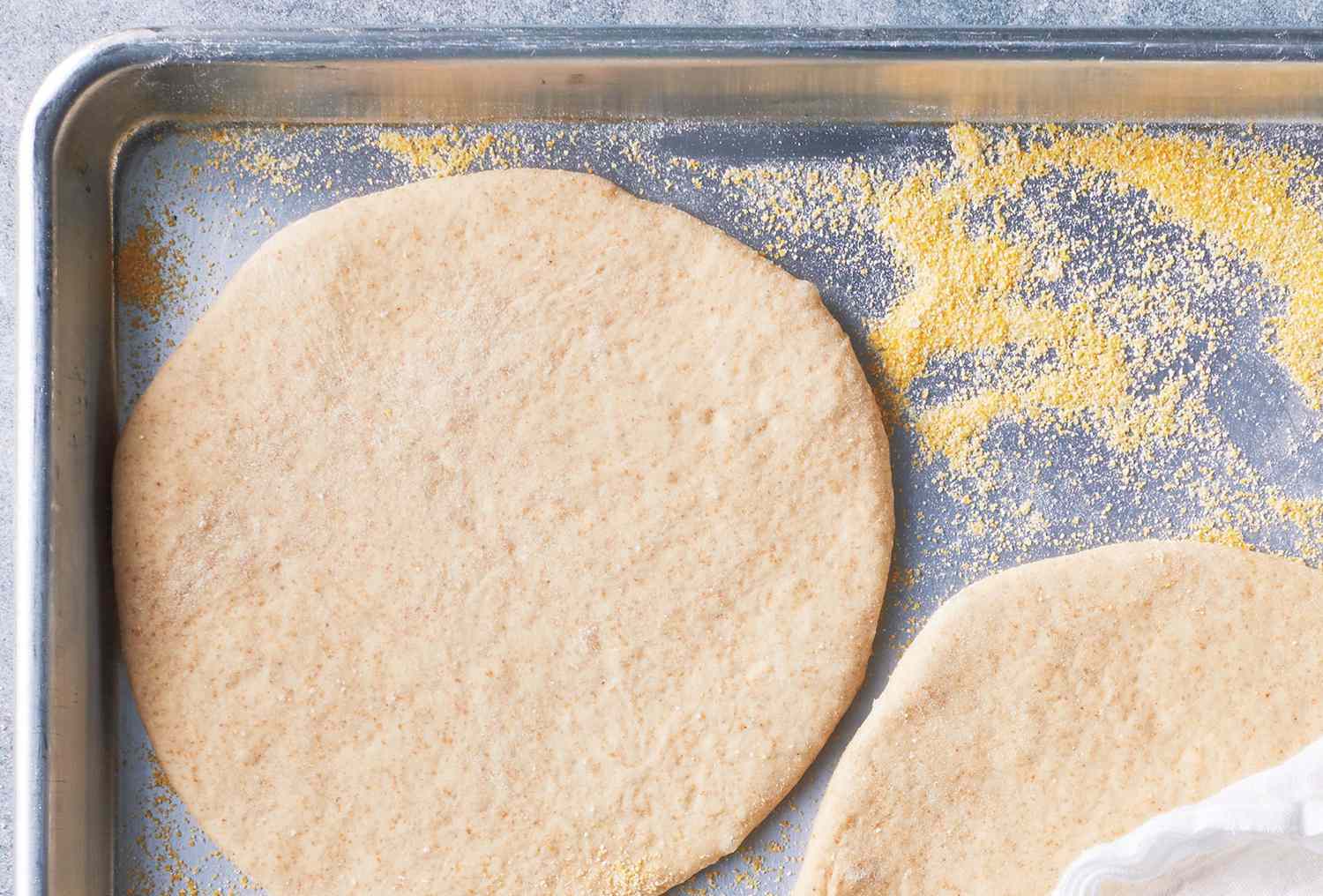 Dough resting on baking sheet with cornmeal