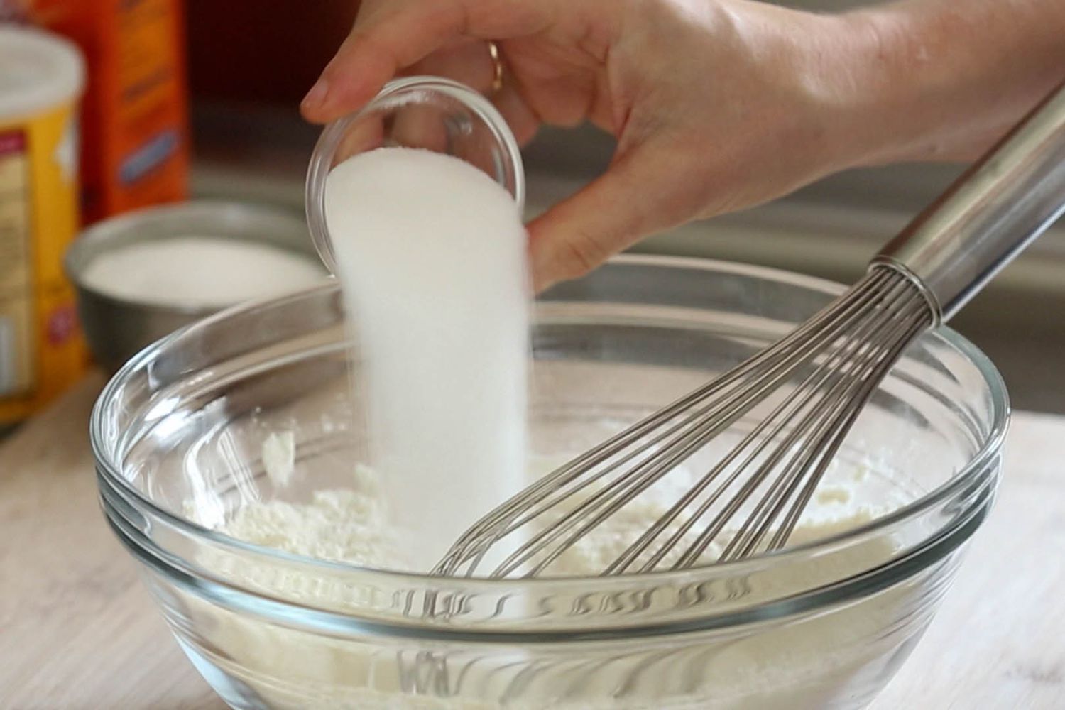 pouring sugar into bowl of flour