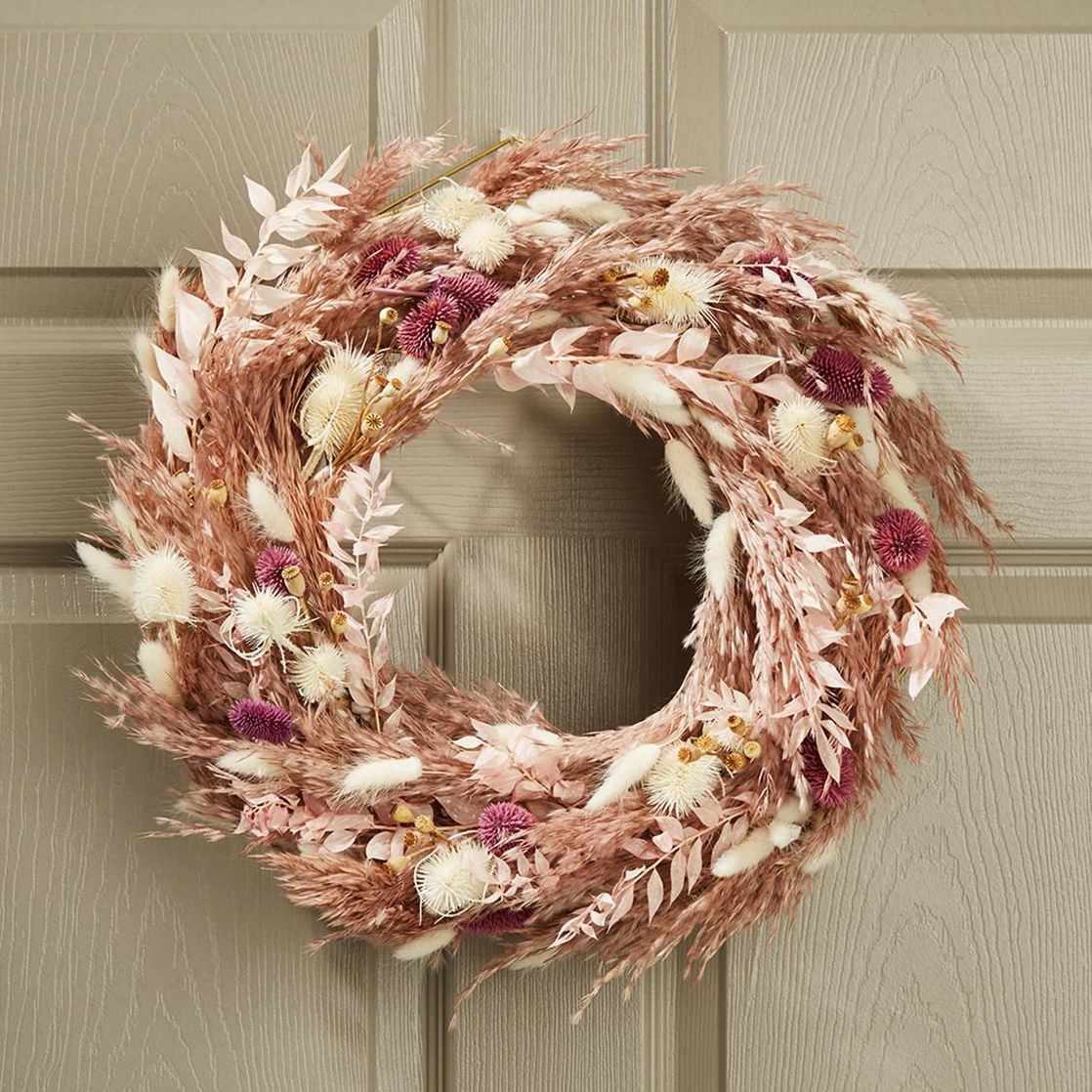 A decorative wreath with dried flowers and foliage hanging on a door