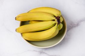 A bowl containing several bananas arranged on a marble surface