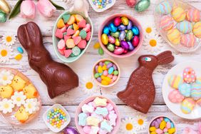 Easter candy table scene. Overhead view over a white wood background. 