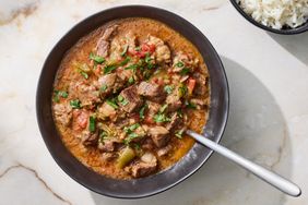 A bowl of carne guisada served with a accompanying bowl of rice