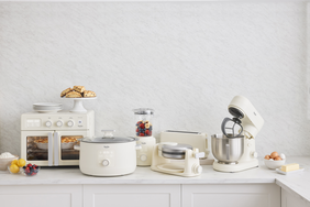 A set of kitchen appliances including a mixer toaster oven blender and slow cooker displayed on a white countertop