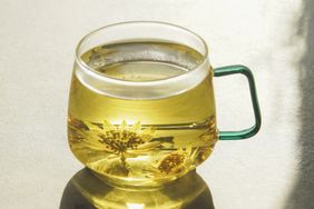 Glass mug of herbal tea with floating flower infusions