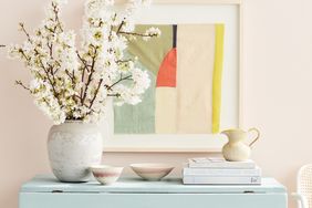 Tabletop arrangement featuring a vase bowls books and a framed abstract painting