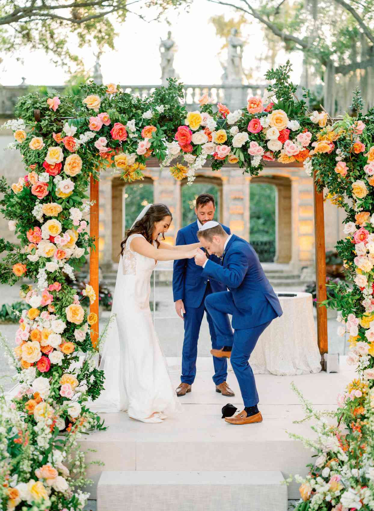 bride and groom breaking glass under chuppah during wedding ceremony