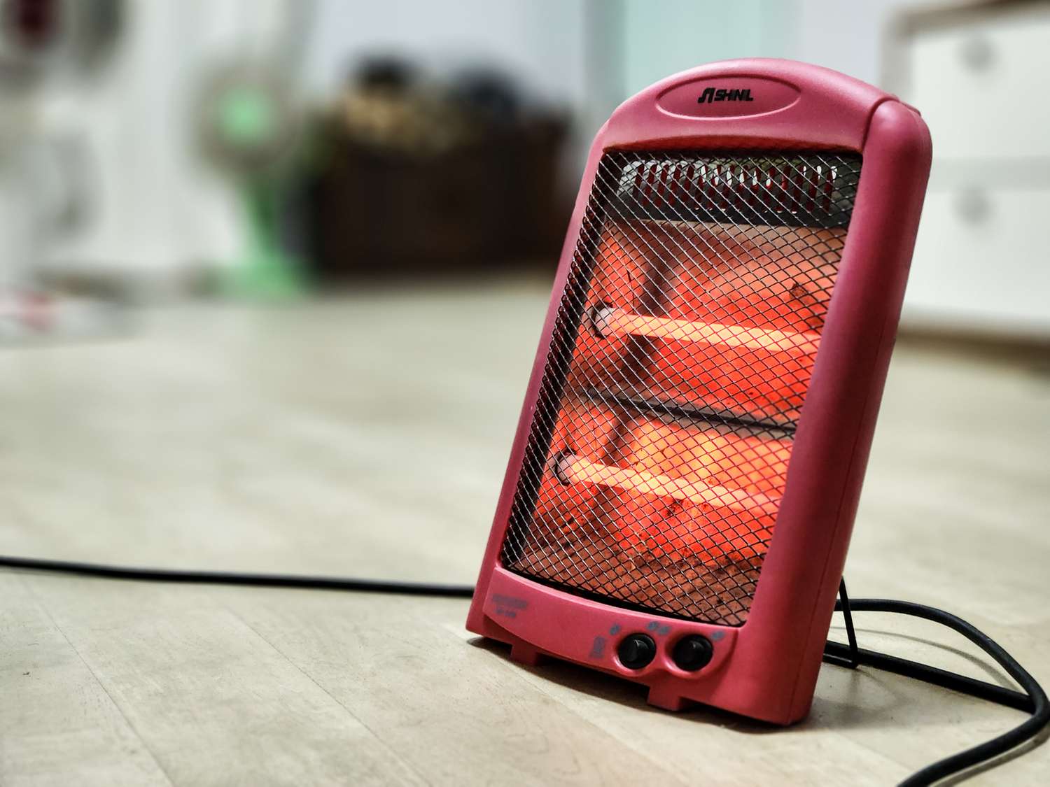 Portable electric heater with glowing heating elements on a wooden floor