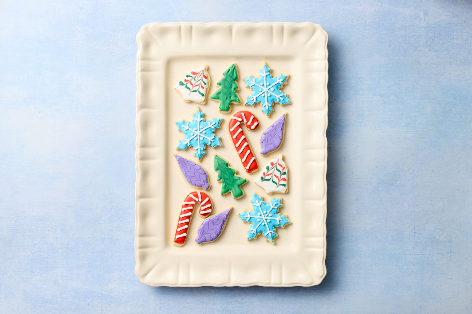 Tray of decorated sugar cookies in festive shapes like snowflakes candy canes and Christmas trees