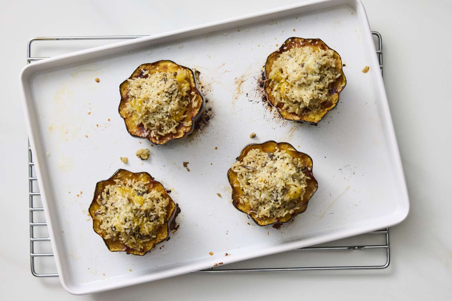 Four acorn squash halves stuffed with a rice mixture baked on a baking sheet