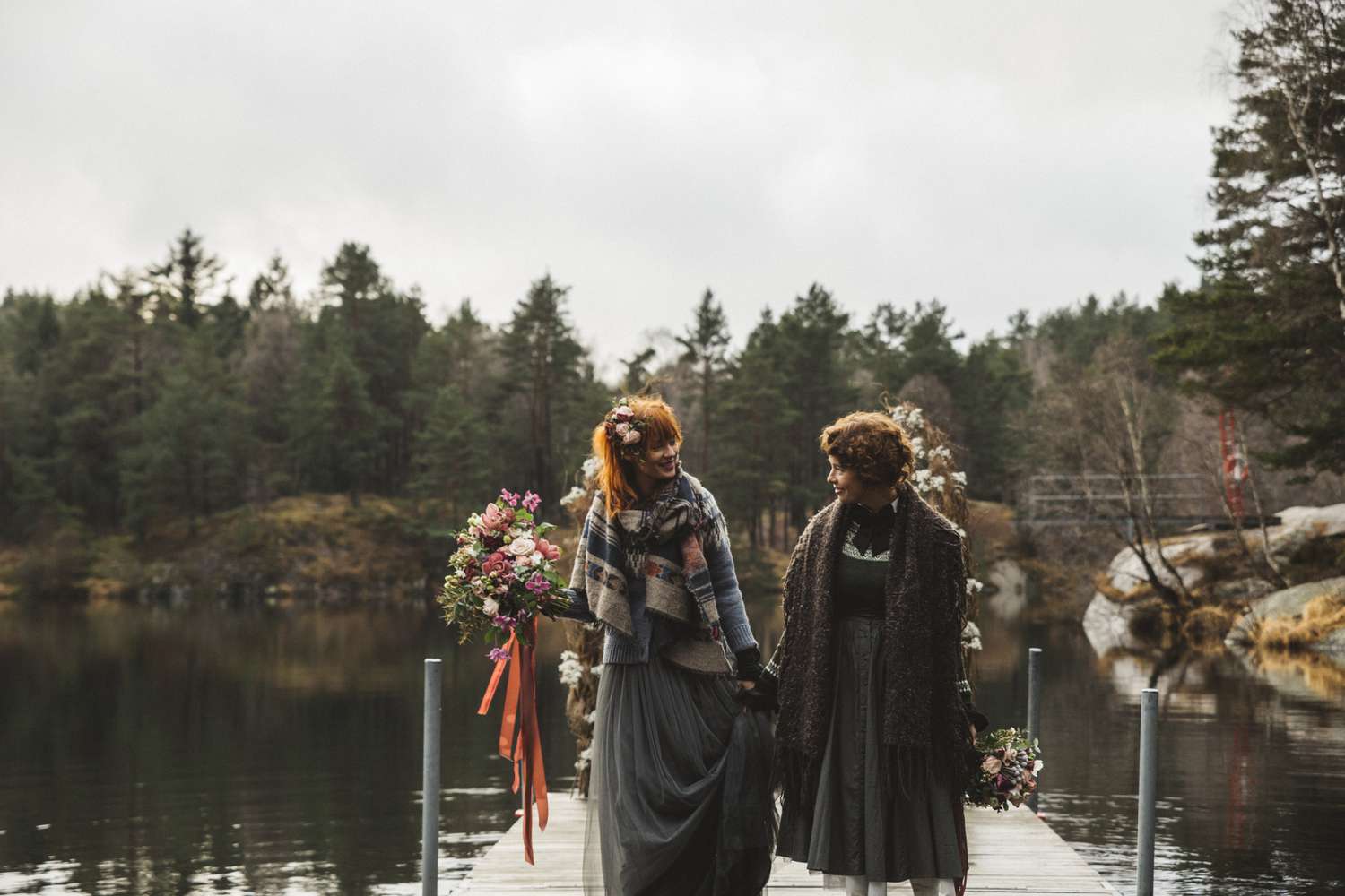 Wedding couple pose by lake with bouquets