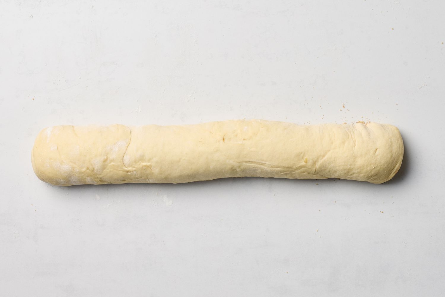 A rolled piece of dough on a white surface