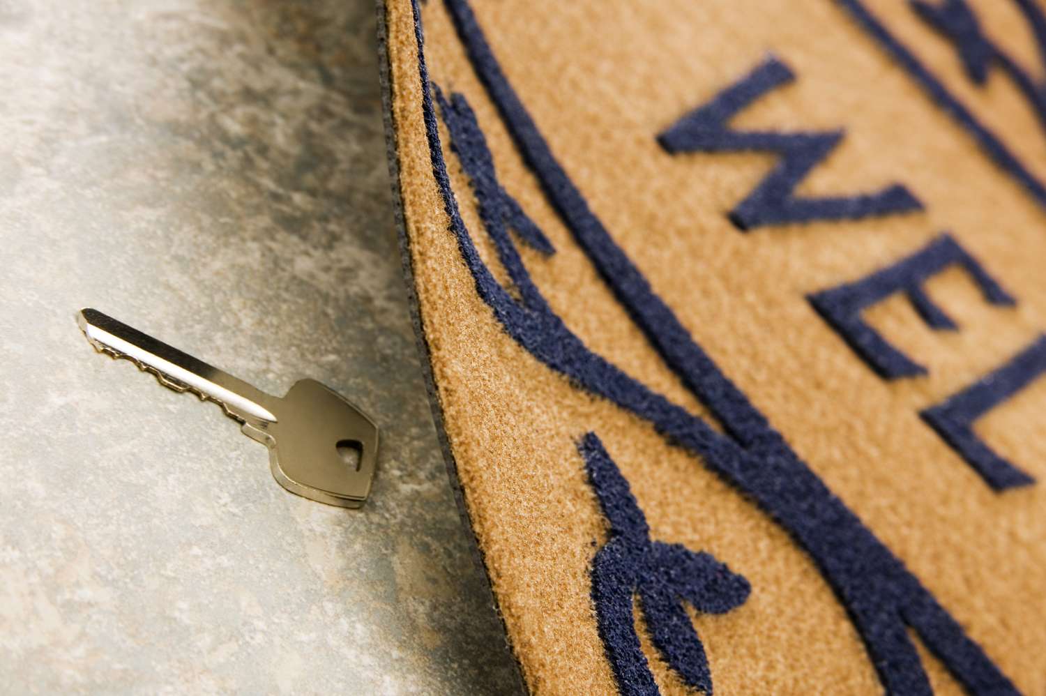 A key placed on a surface next to a doormat with text and patterns visible