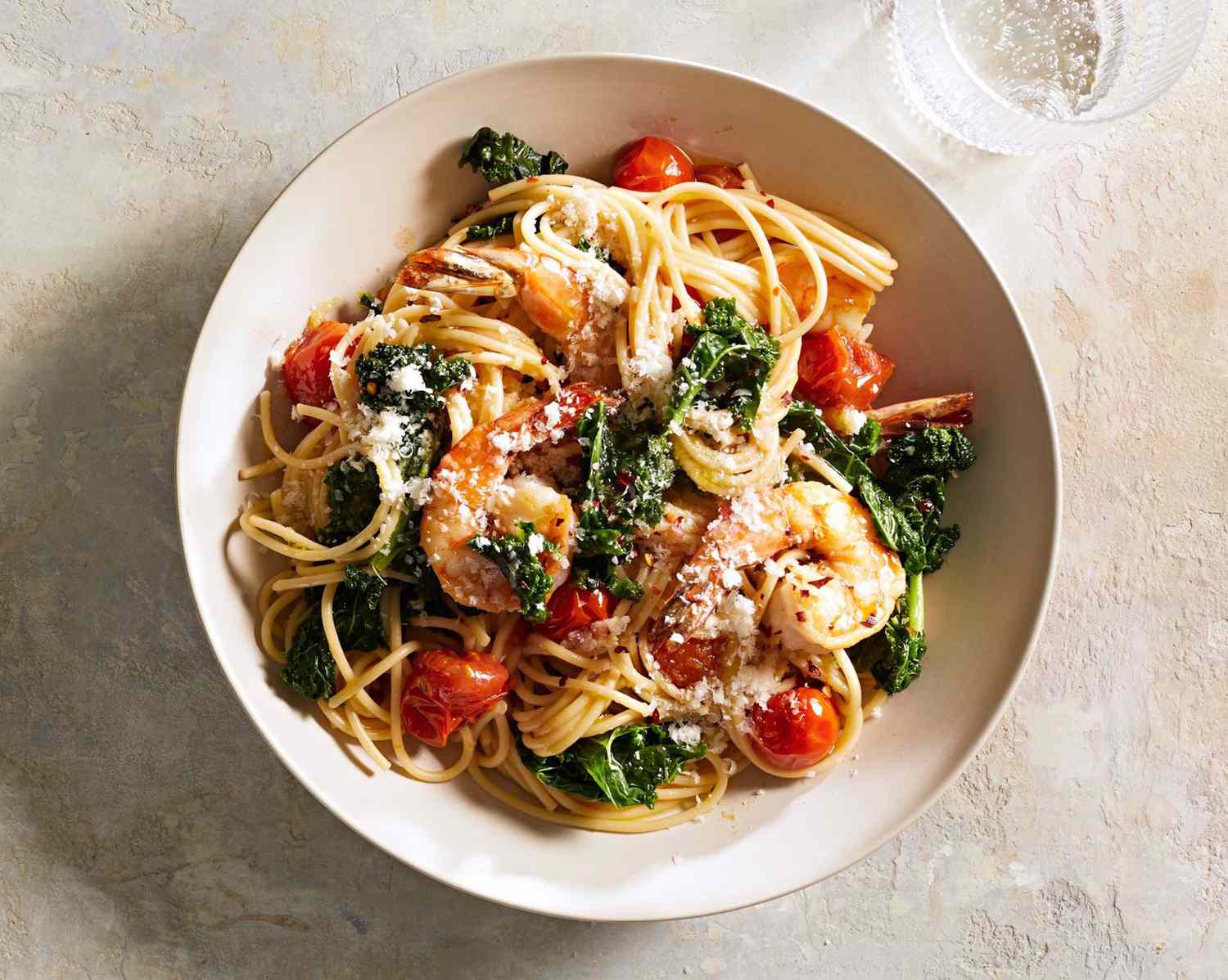A bowl of pasta with shrimp and tomatoes