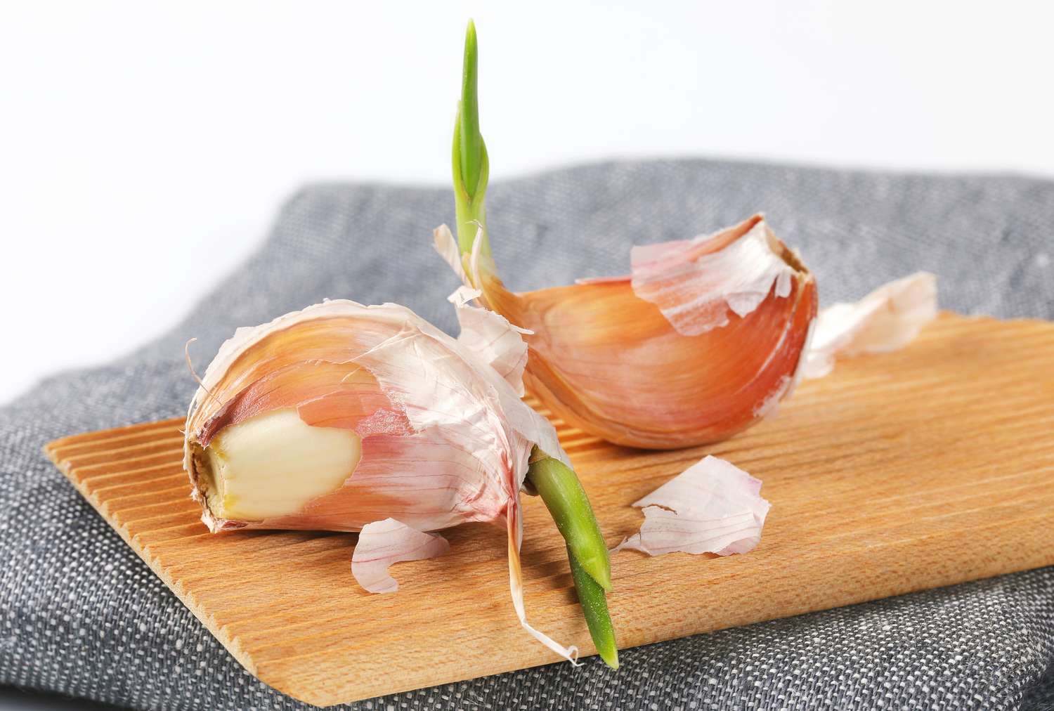 Two sprouted garlic cloves on a wooden surface
