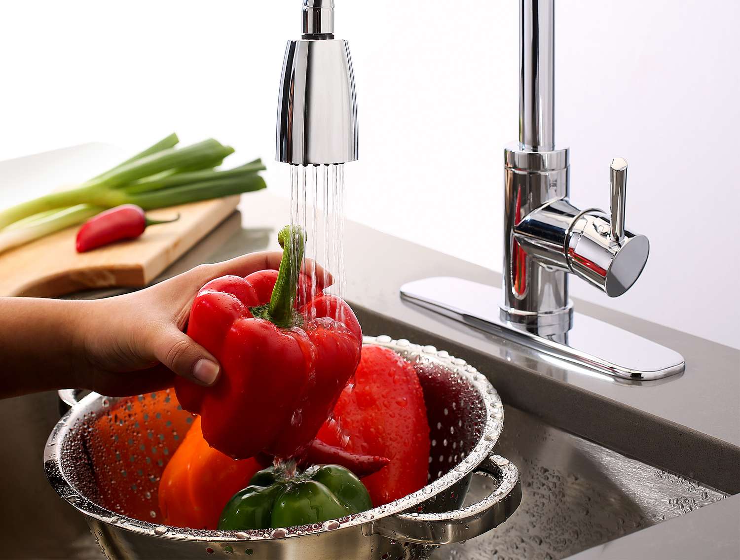 Woman washing peppers under a vegetable sprayer