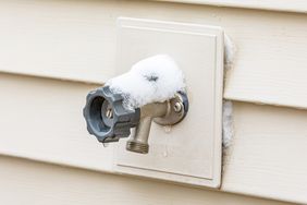 A wallmounted outdoor water spigot with some snow on it