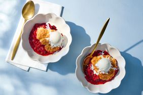 Two bowls of strawberry cobbler topped with scoops of ice cream, accompanied by golden spoons