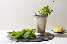 Mint julep on stone slab with lemons and mint