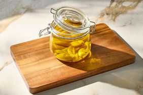A jar of garlic cloves in oil placed on a wooden board