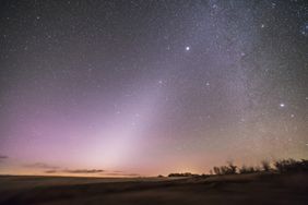 Night sky with starry background and horizon silhouette featuring subtle atmospheric light effects