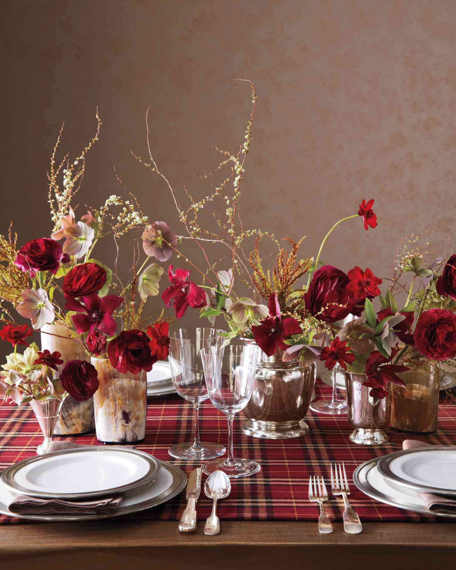 Table setting with red flowers and plaid table runner