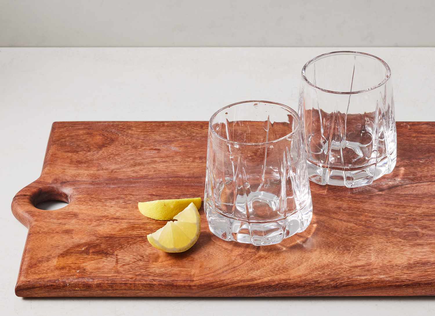 lemon slices and two cocktail glasses on wooden cutting board
