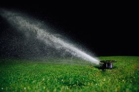 A lawn sprinkler spraying water over a grassy area at night