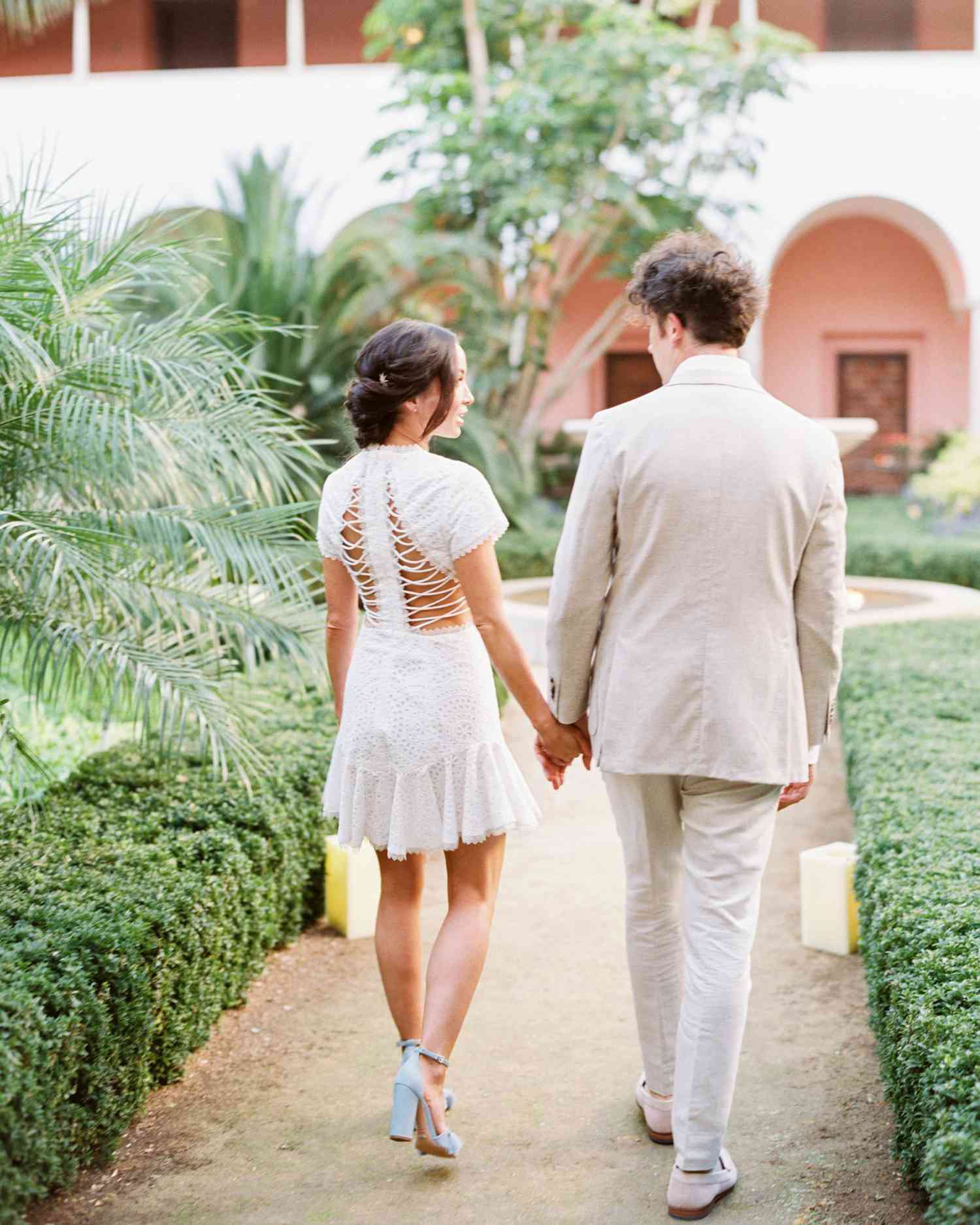 bride and groom holding hands walking down path