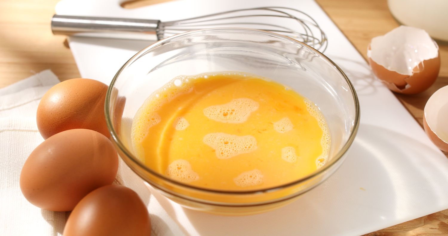 Liquid eggs in a bowl with a whisk. 