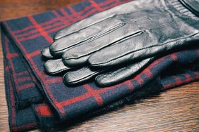 A pair of leather gloves placed on a folded checkered scarf