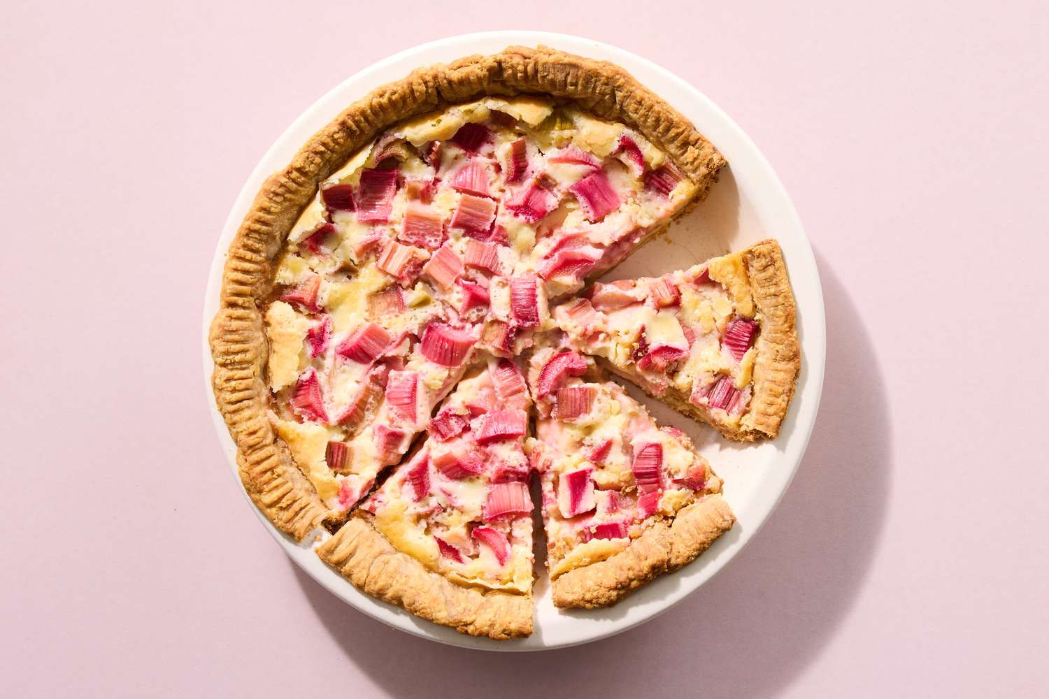 Sliced rhubarb and custard pie on a white plate