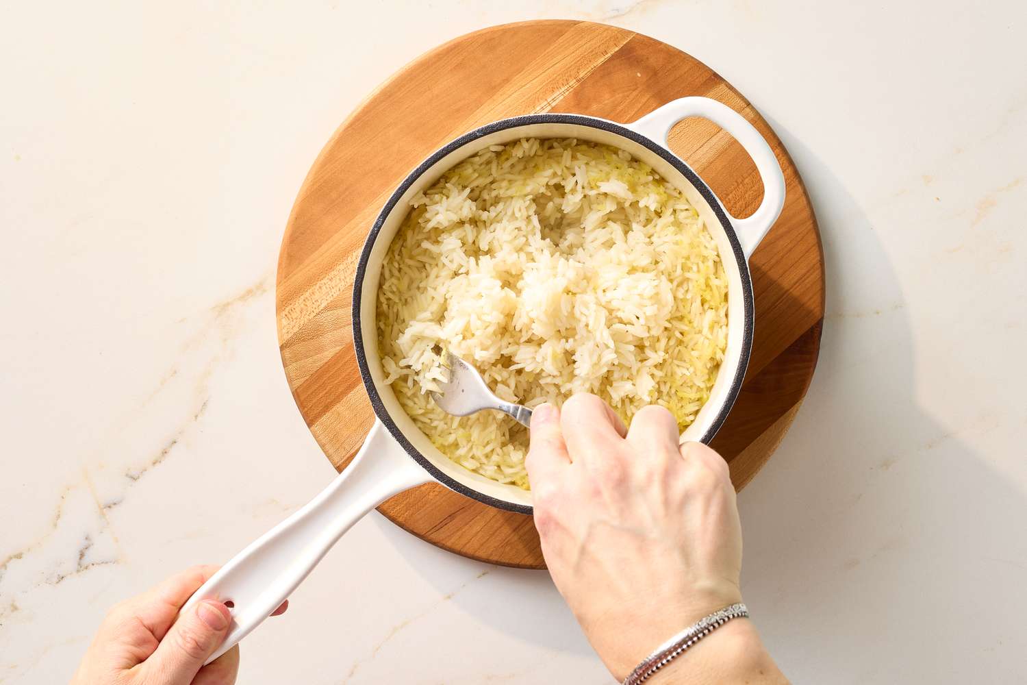 A person fluffing rice in a pot with a fork