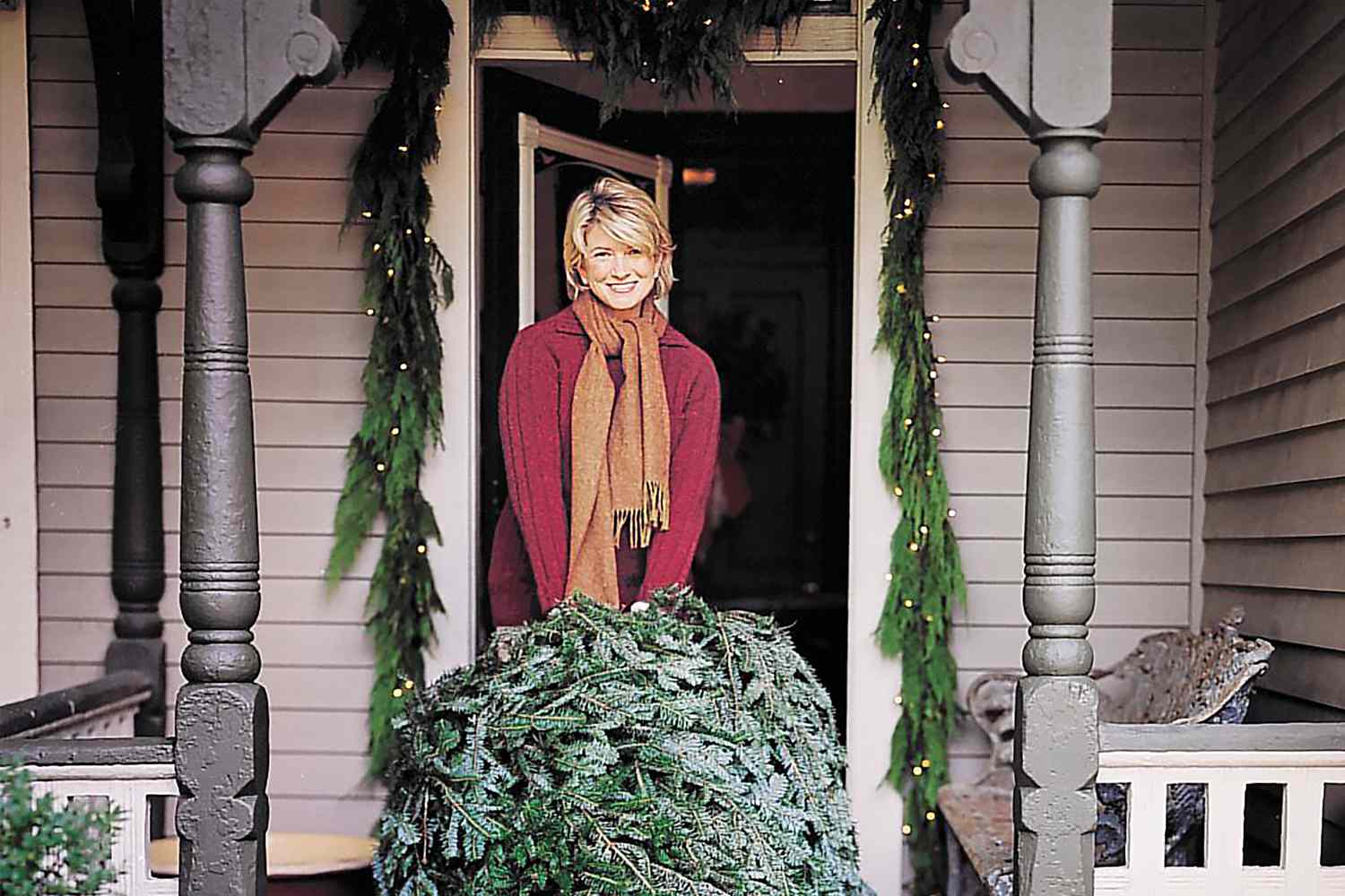decorvow holding a Christmas tree on a front porch