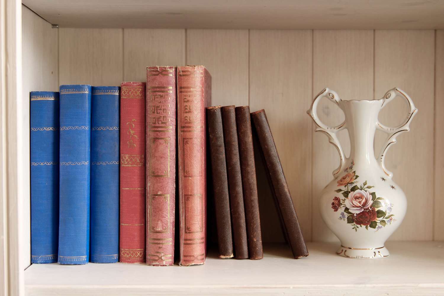 vintage books and a vase on a white bookshelf