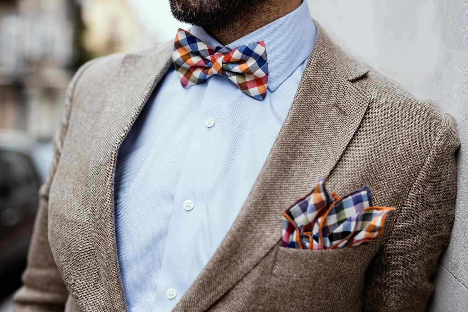 man dressed in a suit with a colorful pocket square and bow tie