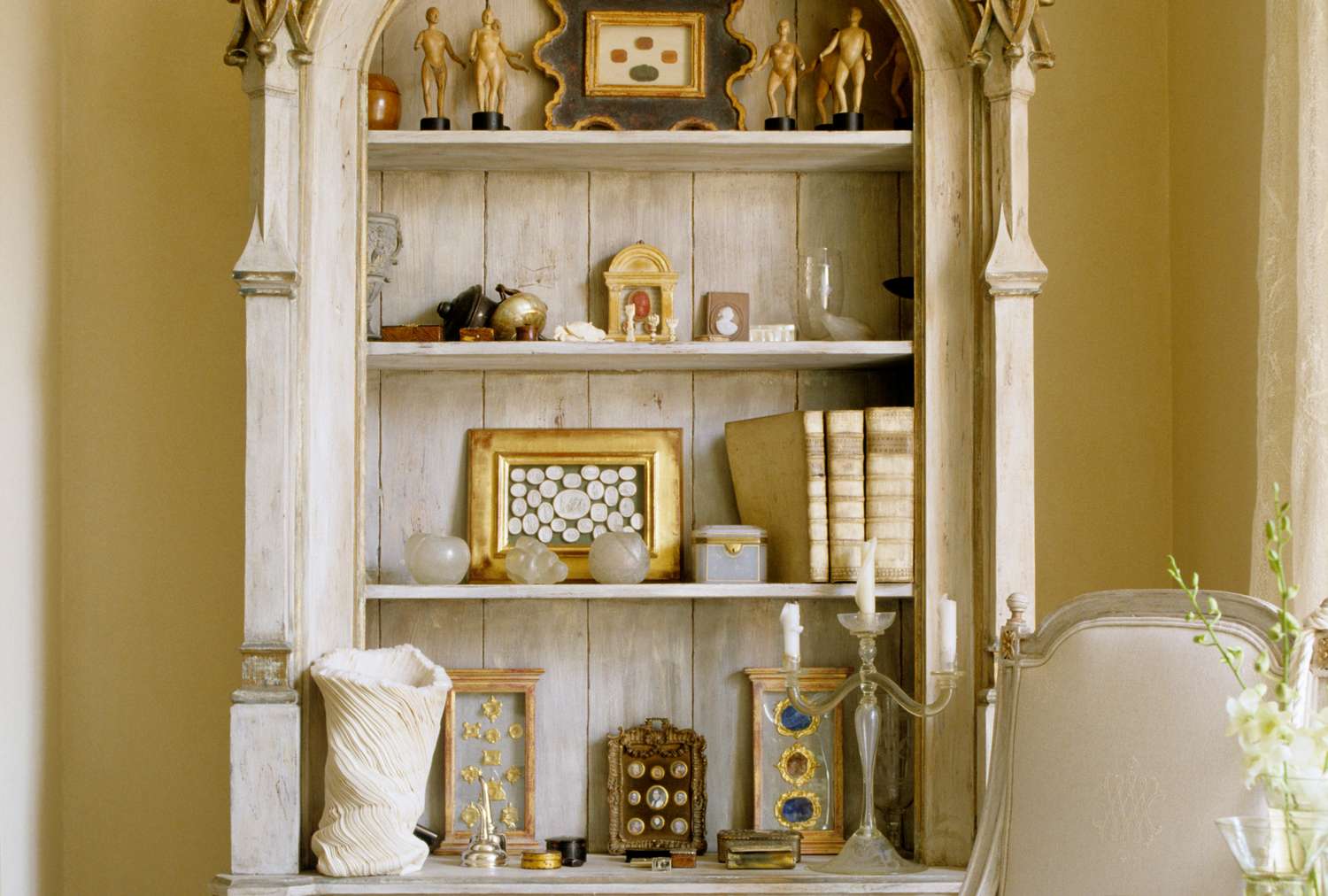 An ornate shelf unit with various antique decorations and books