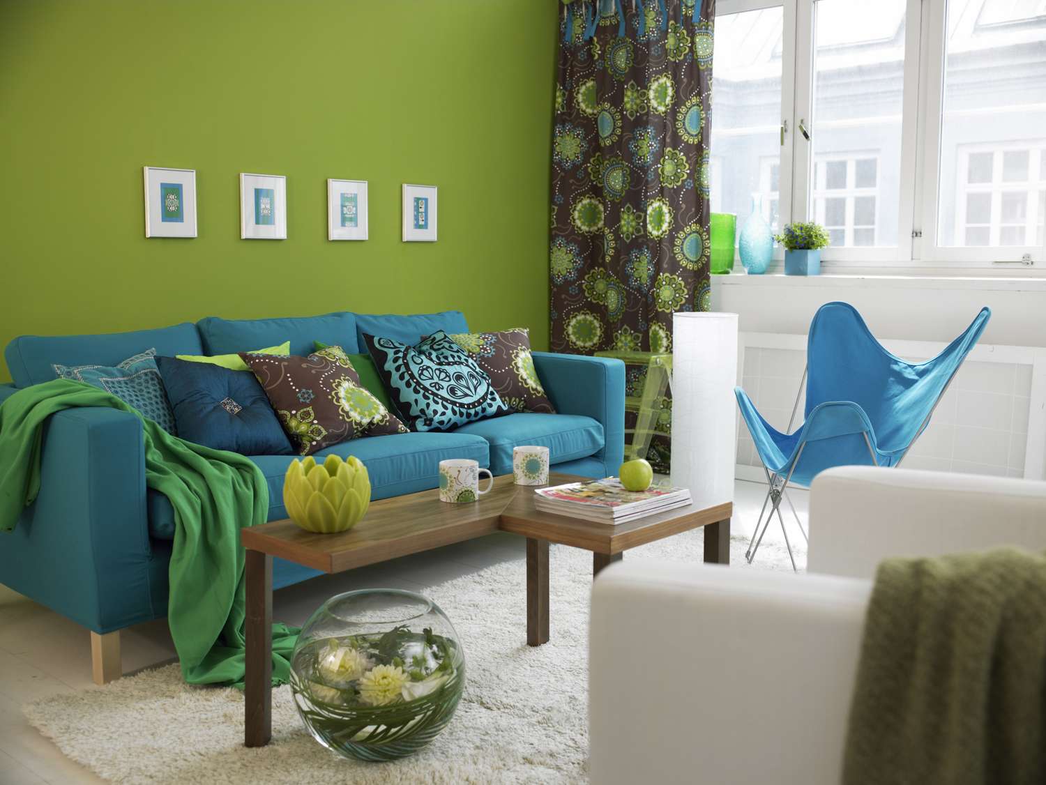 Modern living room with vibrant furniture and decor featuring a blue sofa and green walls