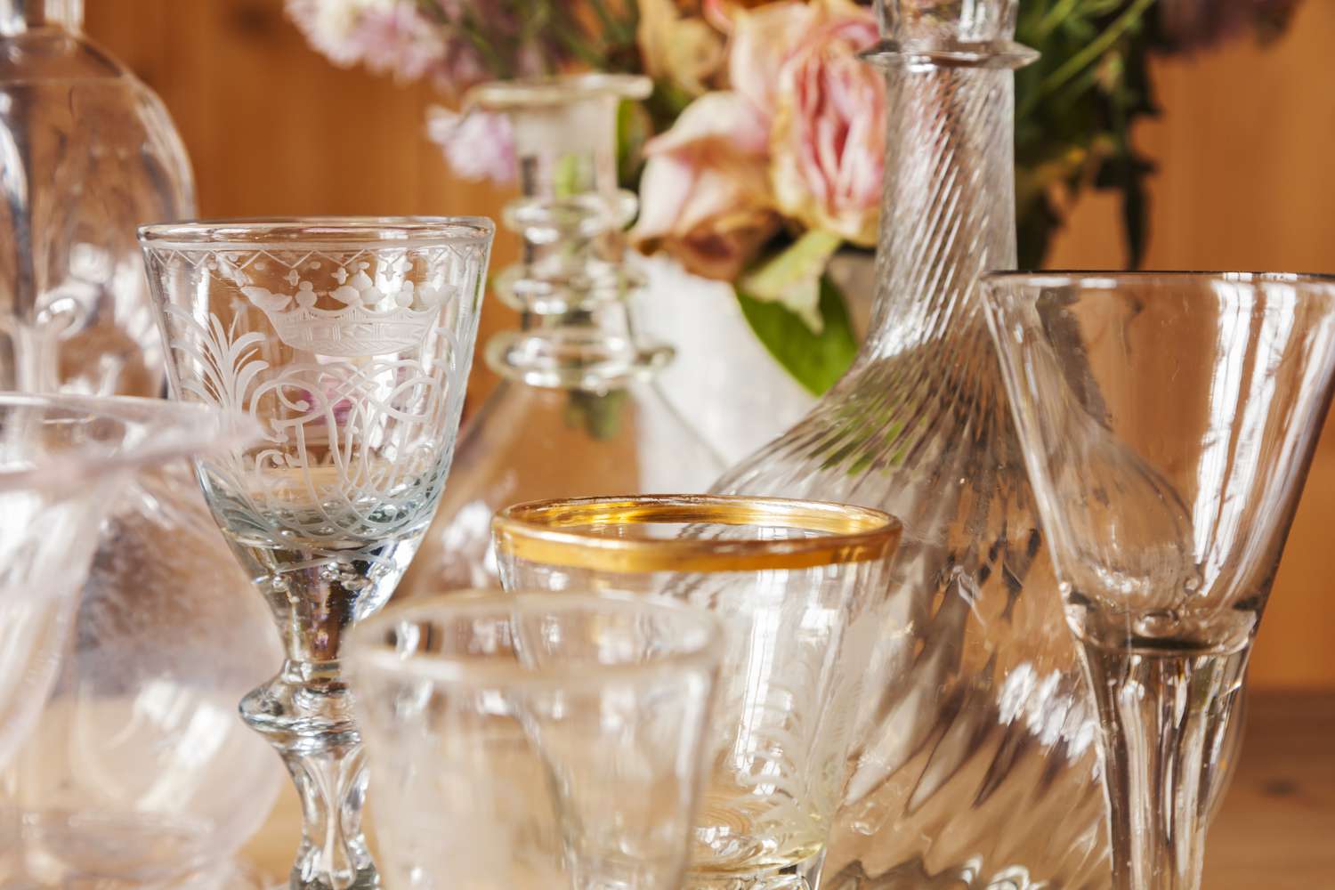 Interior with selection of old wine glasses and carafes arranged with dried roses.