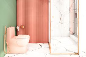 A modern bathroom with a pink toilet, ribbed wall, and glass shower enclosure