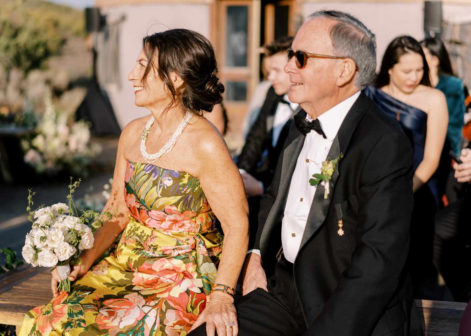 parents of bride and groom sitting on wedding ceremony bench