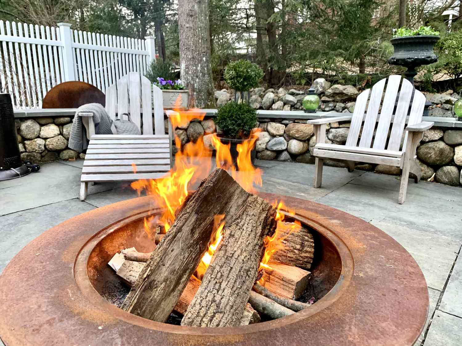 A large metal fire pit is brightly burning
