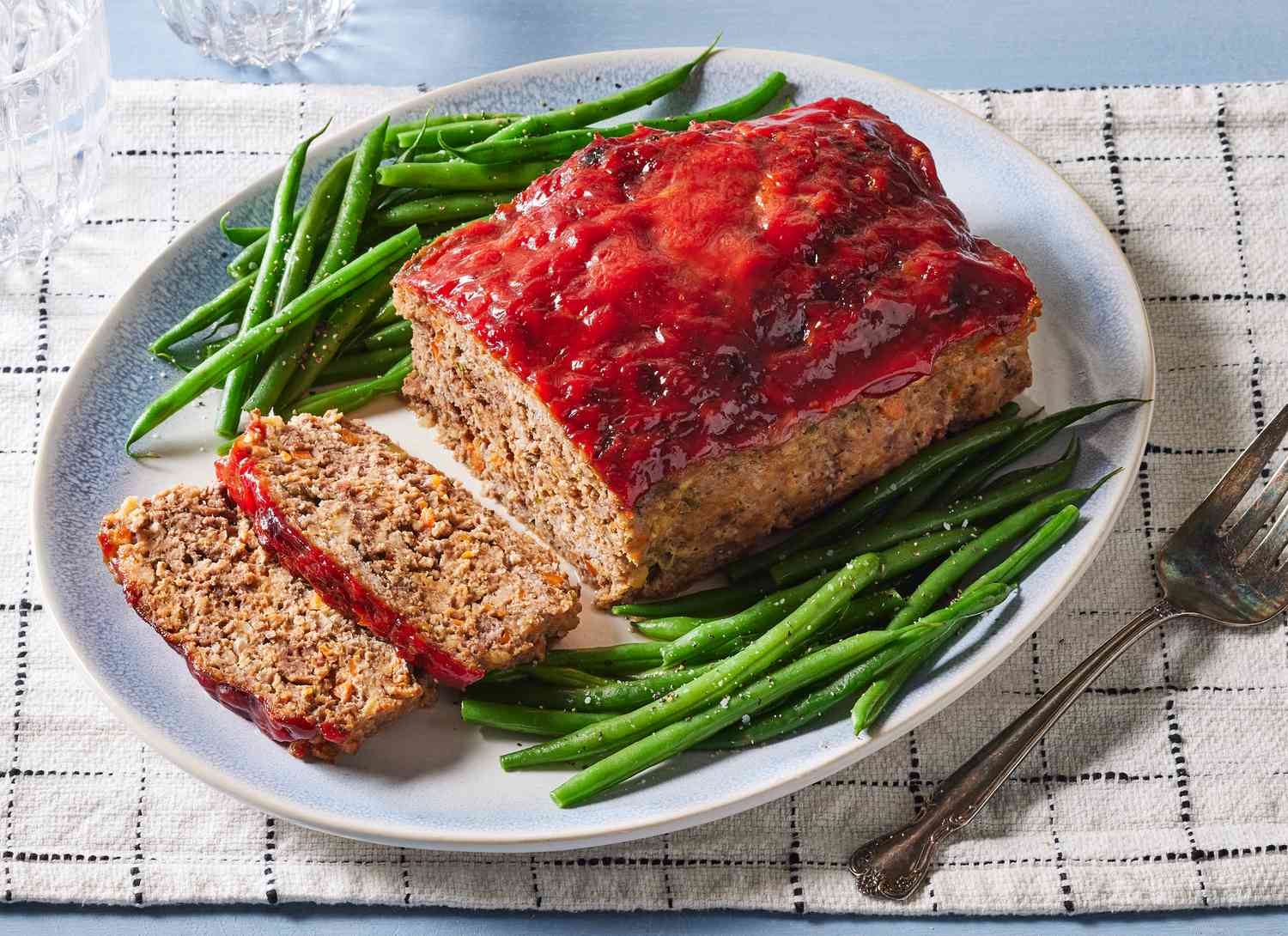 platter of meatloaf with a few slices cut and green beans