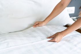 Hands straightening a bed sheet on a bed