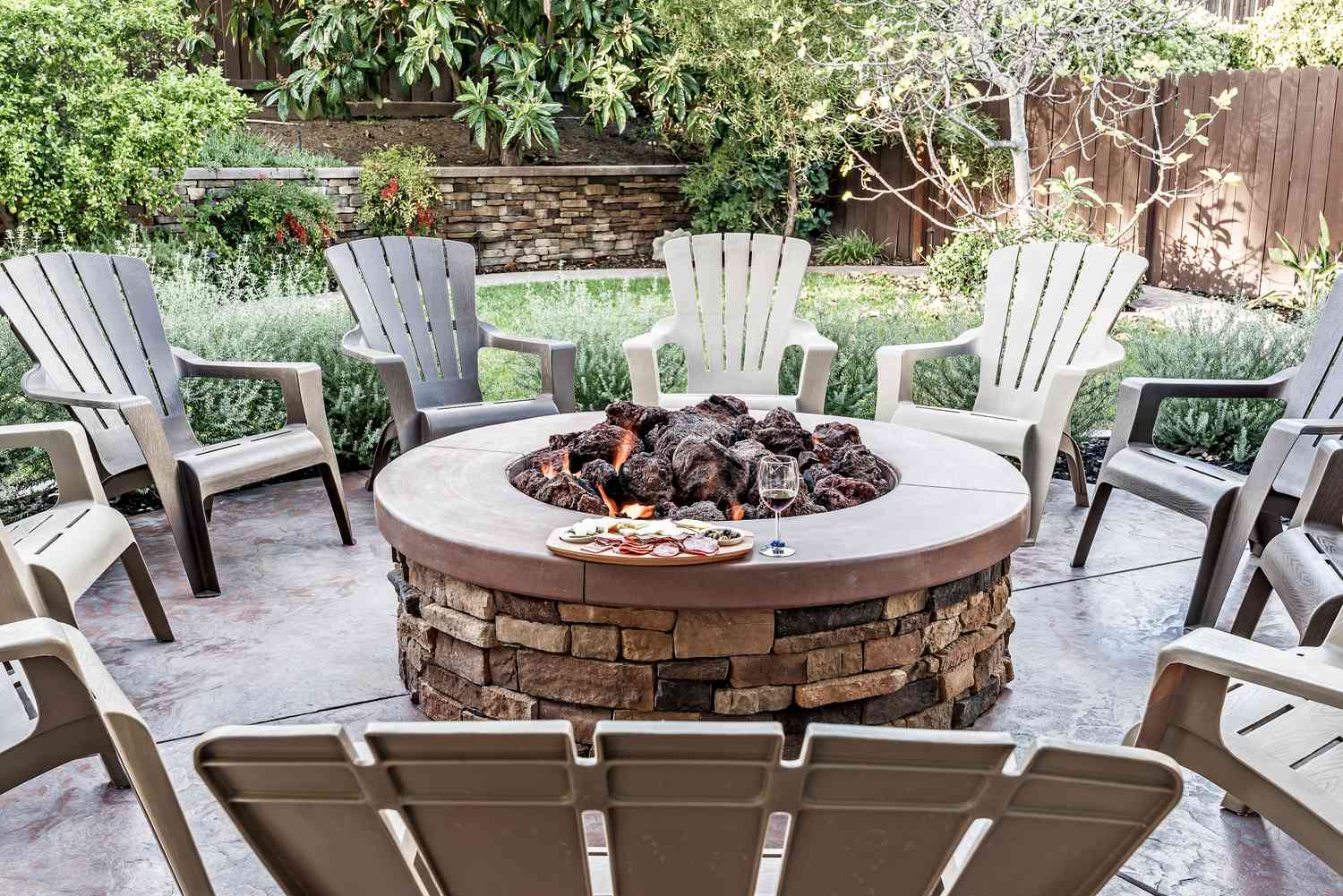 Outdoor seating arranged around a circular fire pit in a garden setting