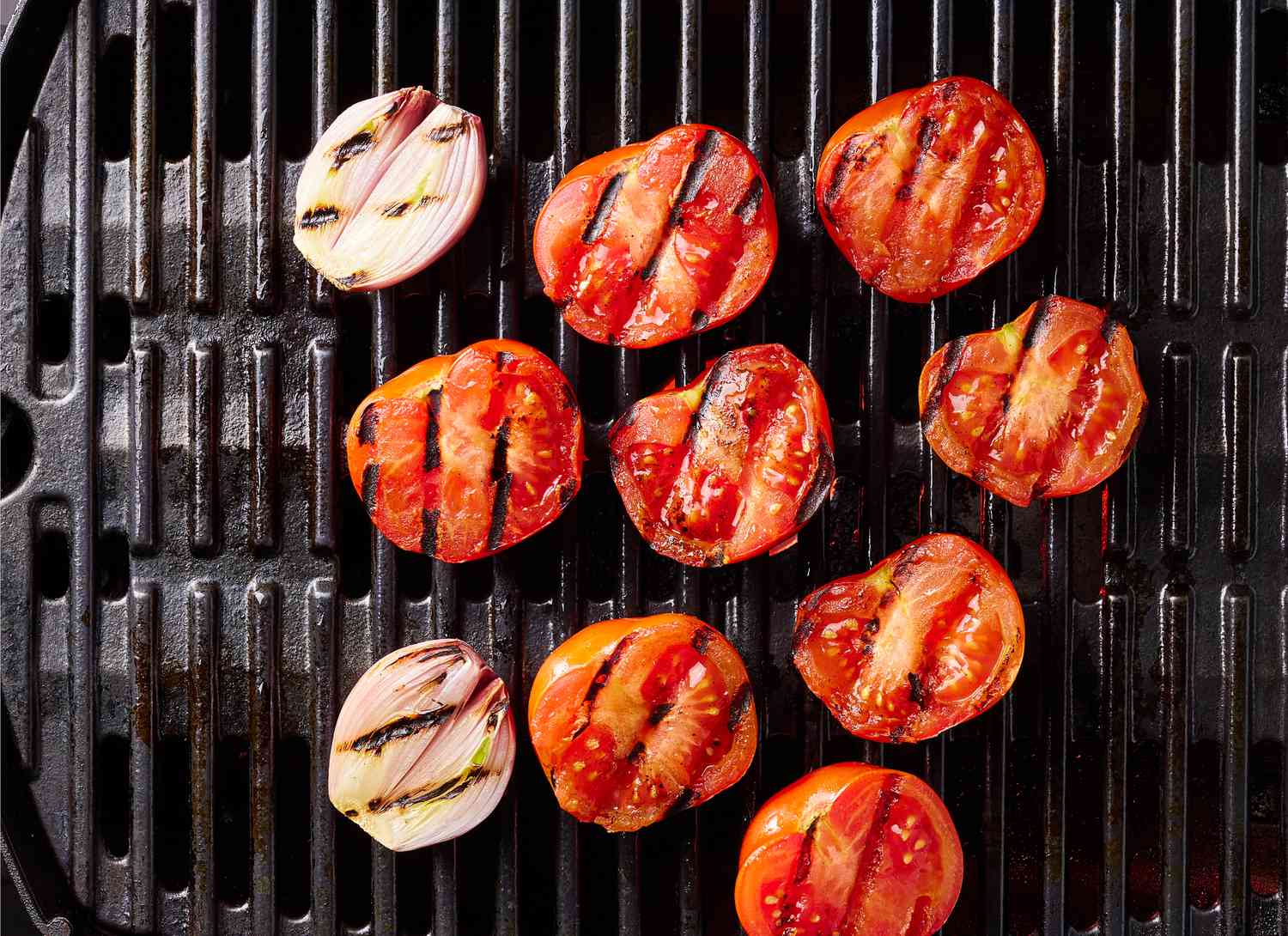 overhead view of sliced tomatoes and onions on a grill