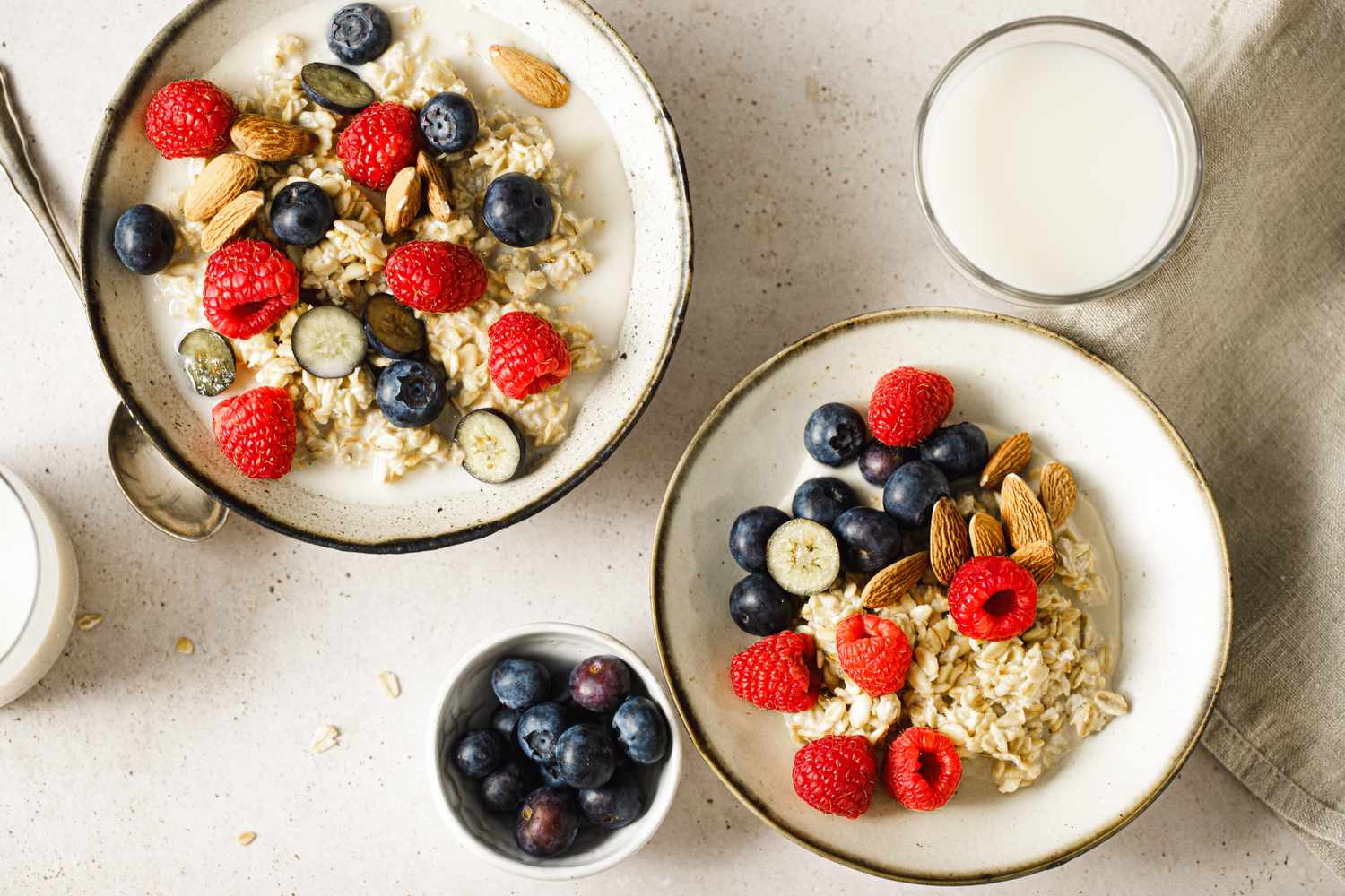 2 white bowls with oats, berries, and almonds