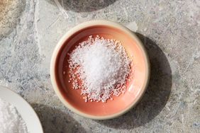 A small mound of coarse salt in a ceramic bowl on a textured surface